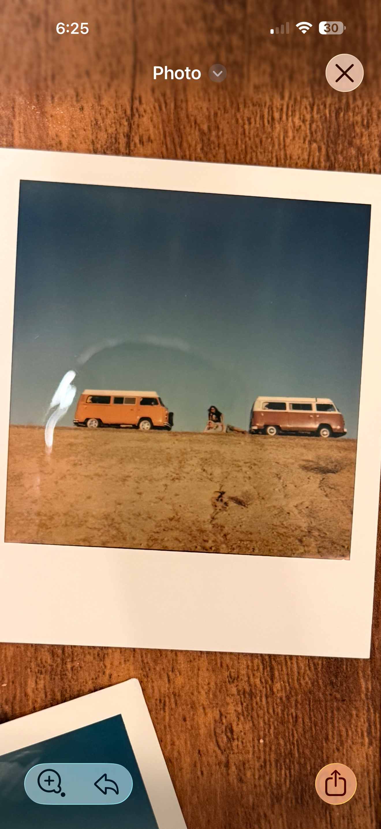 Two vintage Volkswagen Type 2 buses parked side-by-side in open desert with a person sitting between them on the sand